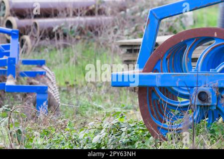 Le attrezzature agricole pesanti blu come l'aratro con dischi in acciaio affilato per la coltivazione agricola su campo con attrezzature trainate da trattore per la preparazione del lavoro sul campo facilitano la meccanizzazione del lavoro agricolo duro Foto Stock