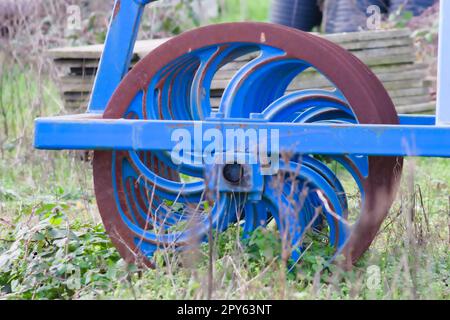 Le attrezzature agricole pesanti blu come l'aratro con dischi in acciaio affilato per la coltivazione agricola su campo con attrezzature trainate da trattore per la preparazione del lavoro sul campo facilitano la meccanizzazione del lavoro agricolo duro Foto Stock