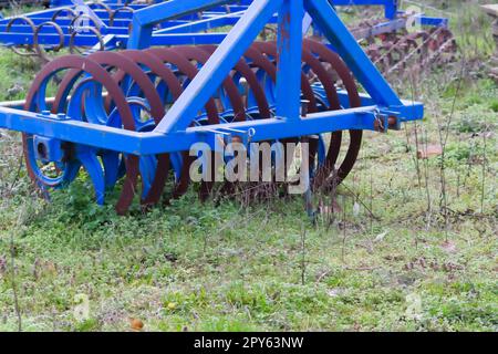 Le attrezzature agricole pesanti blu come l'aratro con dischi in acciaio affilato per la coltivazione agricola su campo con attrezzature trainate da trattore per la preparazione del lavoro sul campo facilitano la meccanizzazione del lavoro agricolo duro Foto Stock