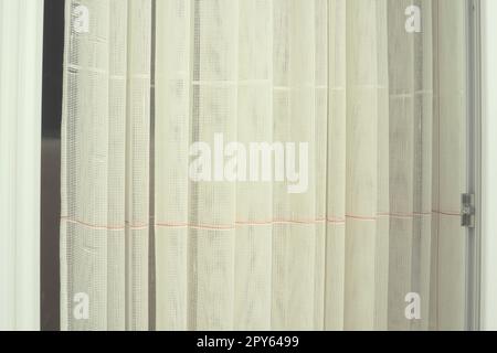 Tende bianche in cotone grossolano o lino fatte di trame di fili sottili. Appartamento interno semplice, compatto ed economico. Decorazione delle finestre in camera. Striscia rossa. Foto Stock