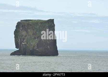 Vista panoramica della penisola islandese con le onde che colpiscono l'enorme roccia nera a Capo Dyrholaey sovrastato Foto Stock