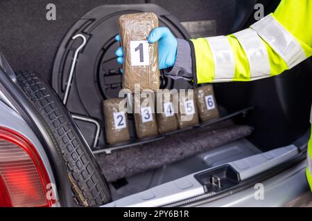 La polizia impadronirsi di droga nel bagagliaio di un veicolo durante arresto del traffico Foto Stock