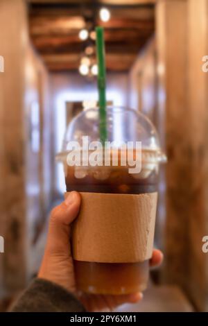 Mano che tiene il caffè freddo con l'arancia Foto Stock