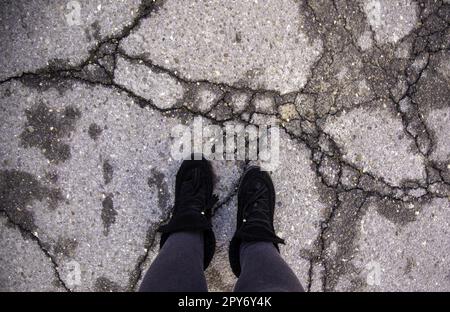 Piedi su asfalto incrinato Foto Stock