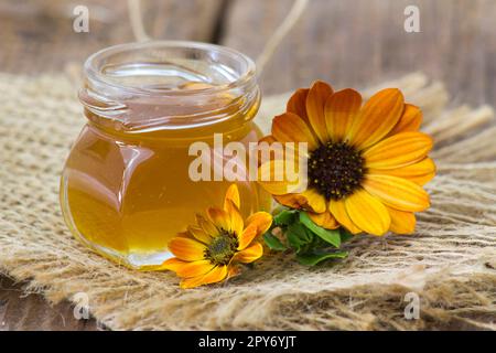 miele e fiori su sfondo di legno Foto Stock