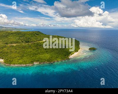 Volando sopra la bella isola tropicale con una piccola isola vicino alla costa bianca della spiaggia che è completamente circondata dall'acqua. Siquijor, Filippine. Foto Stock