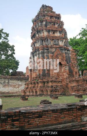 Vista dall'angolo basso del vecchio tempio in rovina e della torre pendente contro il cielo blu di Ayutthaya Foto Stock