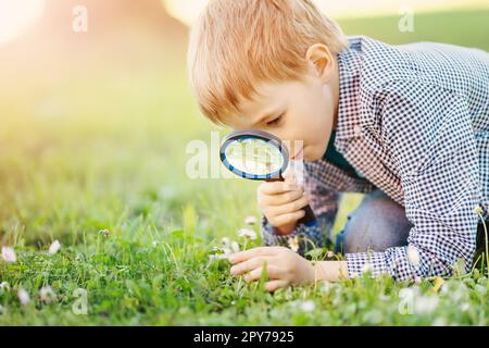 Ragazzo con lente d'ingrandimento che esplora la natura. Foto Stock
