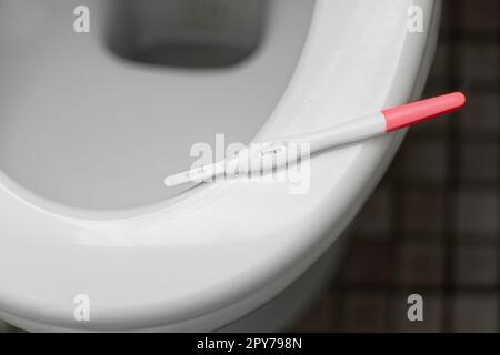 Il bastoncino del test di gravidanza si trova sulla ciotola del WC. Foto Stock