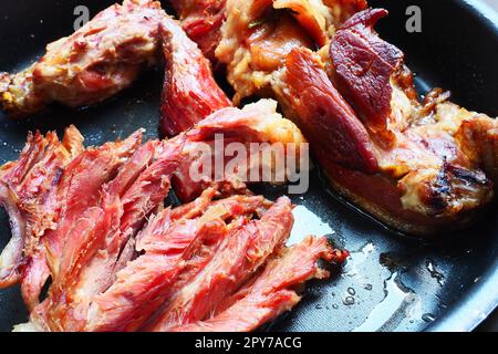 Spalla o ginocchio di maiale affumicato arrosto. Carne deliziosa su una teglia nera con gocce di olio vegetale, estratte dal forno. Prelibatezze di maiale per cena in un ristorante e pranzo in famiglia. Carne rossa Foto Stock