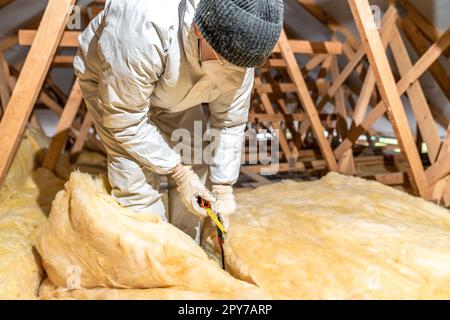 taglio di lana di vetro quando si isola il soffitto sul tetto Foto Stock