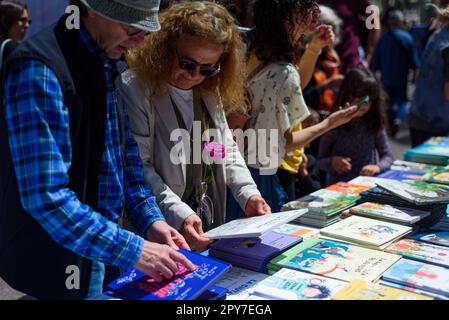 Barcellona, Spagna - 23 aprile 2023: Si vedono persone che acquistano libri mentre tengono rose rosse durante la tradizionale festa catalana di Sant Jordi celebrazioni Foto Stock