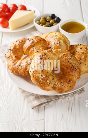 ACMA Turco in stile Soft Bagels servito con pomodoro, formaggio, olio d'oliva e olio di oliva closeup sul piatto sul tavolo. Verticale Foto Stock