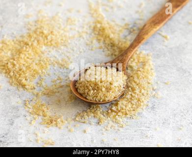 Cucchiaio di legno di bulgur secco crudo grano da vicino, spazio per copia. Cibo sano Foto Stock