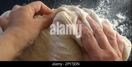 Impastare l'impasto con le mani. La donna ha impastato l'impasto per cuocere o gnocchi. Preparazione di farina, acqua e massa d'uovo per la lavorazione termica. Chef Hands Foto Stock