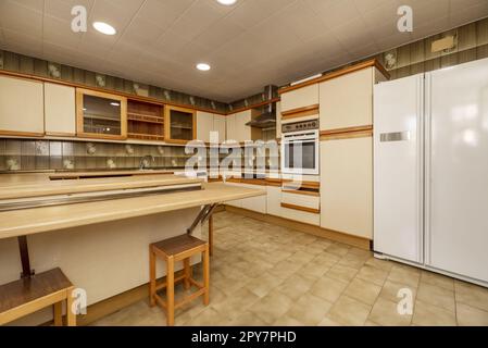 Una spaziosa cucina piena di armadietti color crema con accenti in legno, ripiani chiari e elettrodomestici da incasso Foto Stock