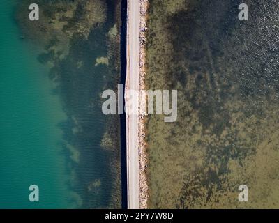 Strada che attraversa il lago. Concetto di viaggio ed esplorazione. Strada in mezzo acqua. Vista aerea del drone. Foto Stock