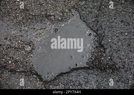 Danni alla strada causati da buche nell'asfalto della carreggiata Foto Stock