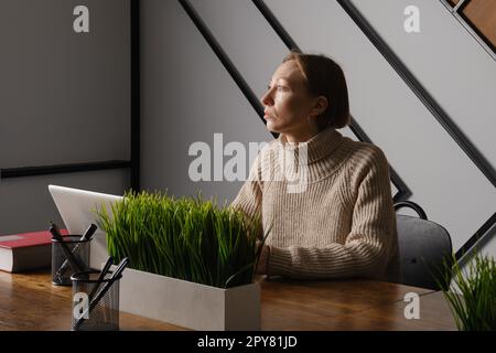 Una donna di mezza età lavora straordinari in ufficio Foto Stock