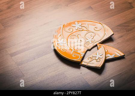 Piastra in ceramica rotta su pavimento in legno Foto Stock