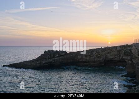 Paesaggi meravigliosi in Portogallo. Costiera panoramica a Cascais. Vista sulla Boca do Inferno al tramonto. Mare increspato. Skerries rocciosi. Pescatore. Sunn Foto Stock