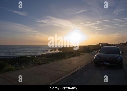 Aldeia de Juzo, Portogallo - 2 aprile 2023: Costiera panoramica ad Aldeia de Juzo. Tramonto dalla strada. Mare ondulato. Skerries rocciosi. Scatto statico di una T nera Foto Stock