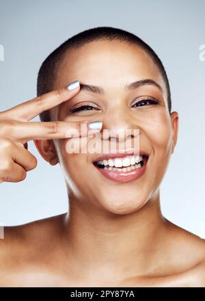 Non nascondersi dietro i capelli. Studio shot di una bella giovane donna in posa con il segno di pace sopra il suo occhio. Foto Stock
