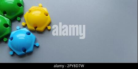 Dettagli multicolore del designer per bambini su sfondo grigio. Dischi di plastica gialli, verdi e blu per lo sviluppo di capacità motorie sottili delle dita Foto Stock
