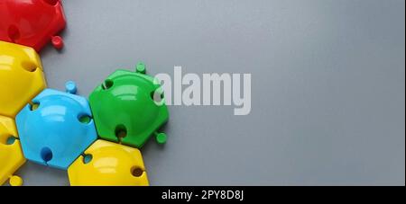 Dettagli multicolore del designer dei bambini su sfondo grigio. Dischi in plastica rosso, giallo, verde, blu per lo sviluppo delle abilità motorie delle dita Foto Stock