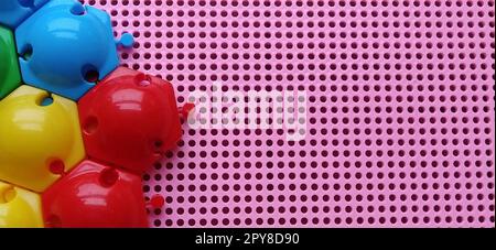 Gioco da tavolo - un mosaico per lo sviluppo delle capacità mentali e creative del bambino. Scatola di plastica rosa con fori. A sinistra, chip e moduli multicolore per creare un grafico. Foto Stock