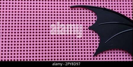 Ala nera in plastica. Pannello rosa con fori per mosaico. Dettagli dei giocattoli per bambini. Foto Stock