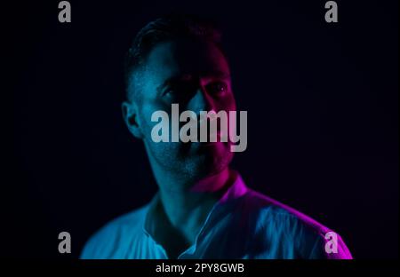 Uomo anziano barbuto in occhiali da sole rave al neon incandescente  guardando lontano su sfondo rosa Foto stock - Alamy