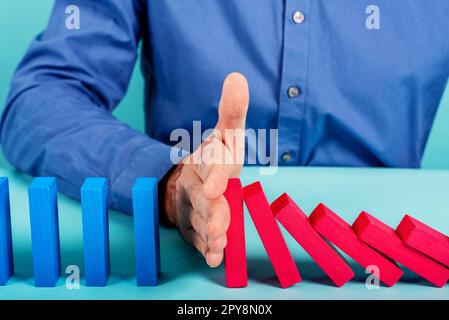 Businessman ferma una catena caduta come gioco domino. Concetto di prevenzione di crisi e fallimento nel business. Foto Stock