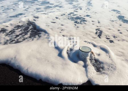 Primo piano tazza in metallo nella foto di concetto di onde schiumose Foto Stock