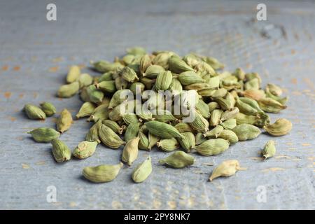 Pila di baccelli di cardamomo secchi su tavola di legno grigio Foto Stock