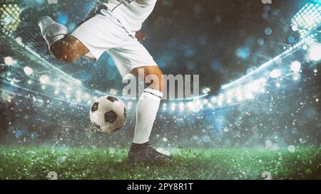 Primo piano di una scena di calcio di notte partita con il giocatore in una divisa bianca che calcia la palla con il potere Foto Stock