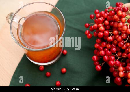 Tazza di tè e frutti di bosco di viburnum freschi e maturi su un tavolo di legno Foto Stock