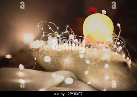 Primo piano luna come lampada e ghirlande luminose su cuscini di lino concept foto Foto Stock