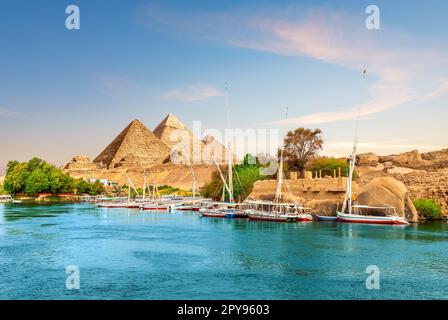 Rocce antiche e barche a vela sulla riva del Nilo, Assuan, Egitto Foto Stock