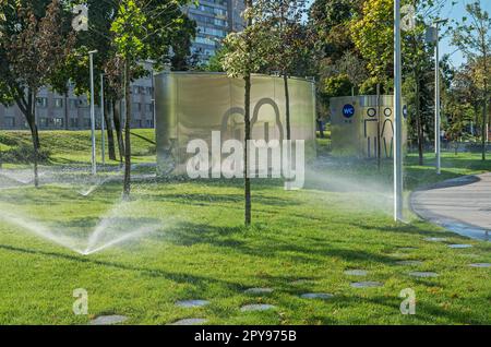 Sistema di irrigazione automatica per prati nel parco cittadino di prima mattina Foto Stock