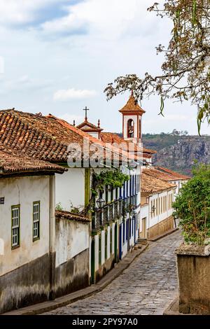 Strada acciottolata nella città di Diamantina con le sue case in stile coloniale e colorati balconi con il campanile della chiesa sullo sfondo, Brasile Foto Stock