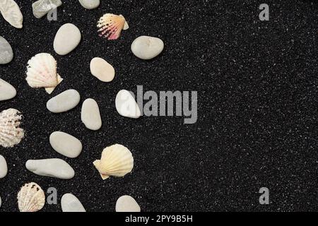 Sabbia nera con conchiglie e ciottoli. Concetto di viaggio e vacanze sfondo Foto Stock