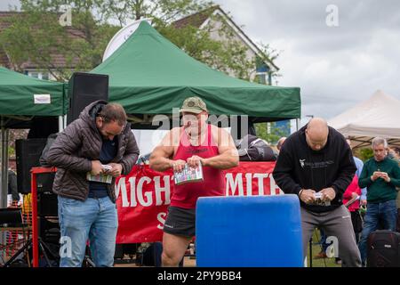 Culcheth, Regno Unito. Lunedì, 1 maggio, 2023, Culcheth, Inghilterra - nonostante i cieli grigi e alcune piovose, Culcheth e Glazebury Community Day sul verde del villaggio che offre intrattenimento da parte del Children’s Entertainer Ian “Zippy” Lees, Northern Stars Dance & Fitness e il Mighty Smith Strongman Show, con sidestalls e luna Park. Adrian Smith compete contro due uomini del pubblico a strappare un catalogo a metà credito: John Hopkins/Alamy Live News Foto Stock