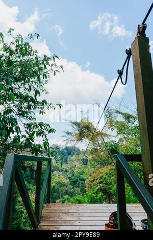 Una piattaforma in legno situata alla fine di una zipline, con vegetazione lussureggiante sullo sfondo Foto Stock