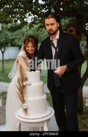 gli sposi novelli tagliano e assaggiano la torta nuziale Foto Stock