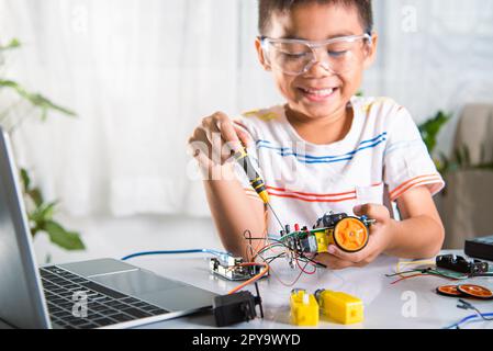 Ragazzo asiatico che monta il progetto di lavoro dell'auto robot Arduino a casa Foto Stock