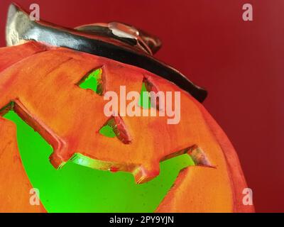 Zucca arancione brillante di Halloween. Praticare fori per bocca, naso e occhi. Luce verde spaventosa dall'interno della zucca. Primo piano. La sinistra risata del mostro. Sfocatura Foto Stock