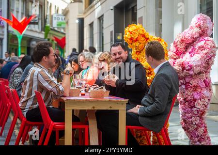 Londra, Regno Unito. 3 maggio 2023. I personaggi in costume intrattengono gli ospiti che cenano in un tavolo da banchetto lungo 80 metri a carter Lane vicino a Fleet Street, come parte del "BIG picnic" del quartiere Fleet Street. Ispirato ai giardini di Highgrove e in onore dell’ammirazione dei fiori selvatici di re Carlo III, l’evento è una delle prime celebrazioni pubbliche per l’incoronazione di re Carlo III Le attività pomeridiane all'aperto a carter Lane, Bream's Buildings e Gough Square proseguono fino a giovedì 4 maggio. Credit: Stephen Chung / EMPICS / Alamy Live News Foto Stock