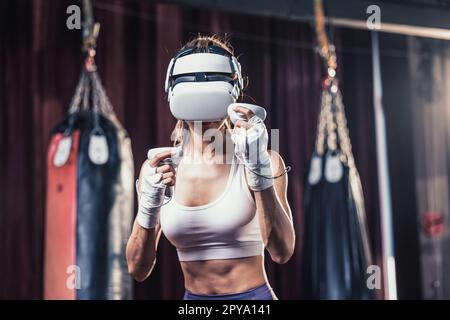 Gli amanti del fitness combattono contro altri membri della palestra indossando occhiali per realtà virtuale durante intensi esercizi di boxe. Imparare e migliorare la tecnologia di boxe Foto Stock