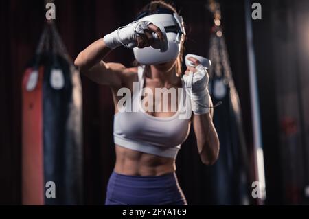 Gli amanti del fitness combattono contro altri membri della palestra indossando occhiali per realtà virtuale durante intensi esercizi di boxe. Imparare e migliorare la tecnologia di boxe Foto Stock